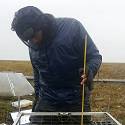 Researcher taking measurements in field.